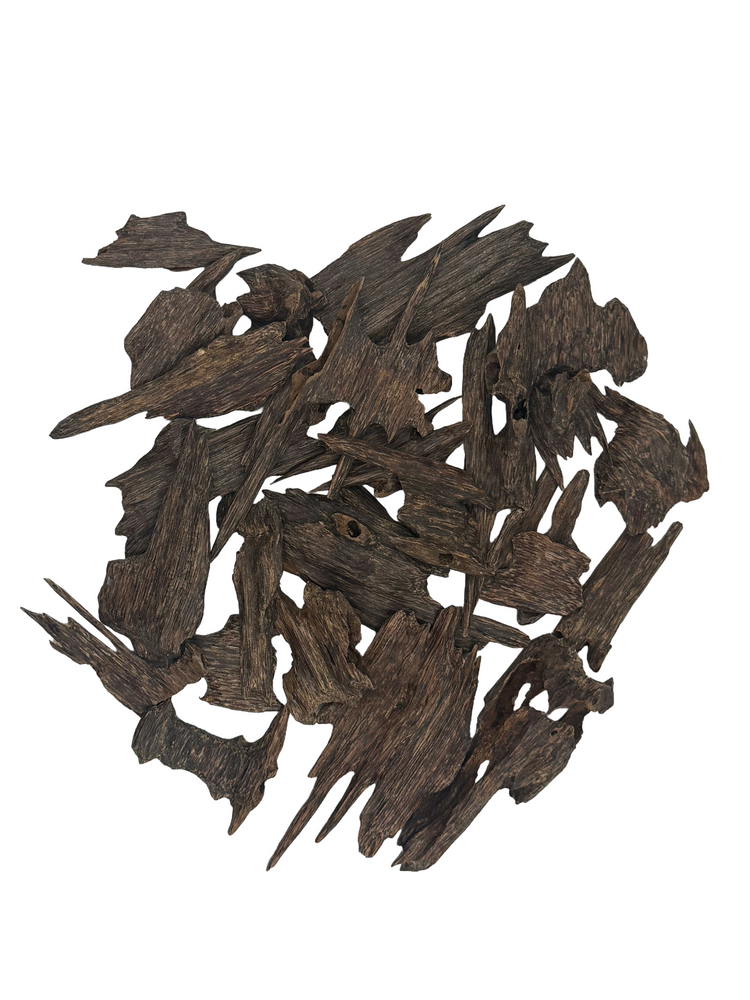 A pile of dark brown wood chips or bark pieces on a solid white background.